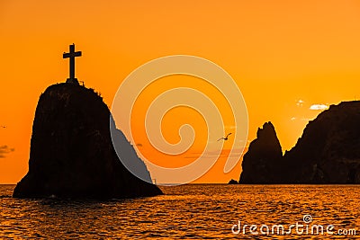 A red burning sunset with the silhouett of a cliff over the sea Stock Photo