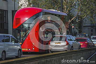 Red bus moving with cars on road in city during sunny day Editorial Stock Photo