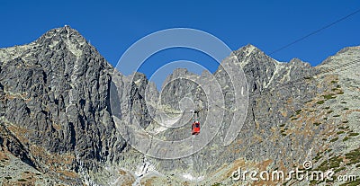 A red cable car on its way from Skalnate pleso to Lomnicky peak. Red gondola moving up to Lomnica peak in High Tatras Mountains. Stock Photo