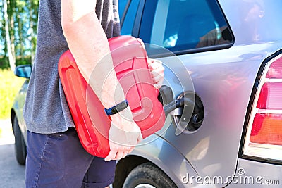 Red canister in the hands of a man. Filling a stalled car with gasoline from a canister Stock Photo