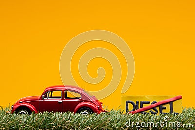 Chisinau 20.02.2020:A red car figurine aligned to the left on grass next to a sign which has the word diesel cut Stock Photo