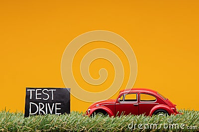 Chisinau 20.02.2020:A red car figurine aligned to the right on grass next to a sign which says test drive Stock Photo