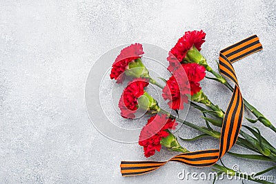Red carnations and St. George ribbon on a concrete background. Symbol may 9, victory day Copy space Stock Photo