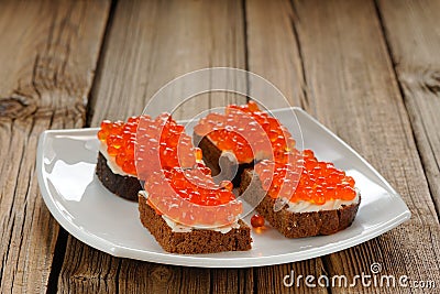 Red caviar on rye bread and butter on white plate Stock Photo