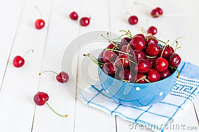 Red cherries in bowl on white wooden background on blue towel Stock Photo