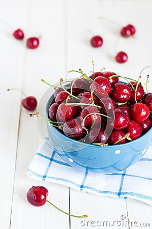 Red cherries in bowl on white wooden background on blue towel Stock Photo