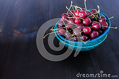 Red cherries in green ceramic bowl on dark background Stock Photo