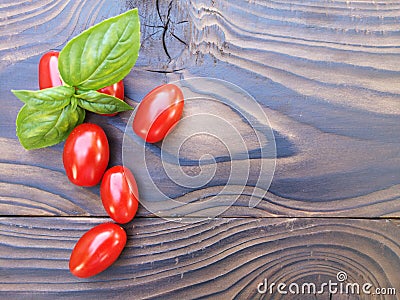 Red cherry tomatoes and basil leaves on a wooden background. Selective focus. Local products consumption concept. Healthy eating Stock Photo