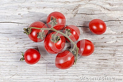 Red cherry tomatoes on withered branch on old wooden surface Stock Photo