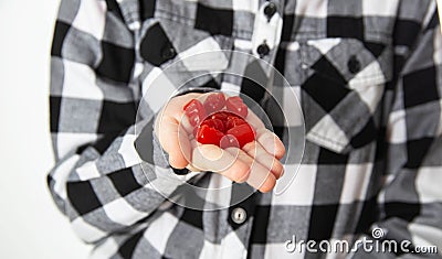 Red chewable vitamins on the palm of a girl s hand against the background of a plaid shirt, close-up. The concept of a Stock Photo