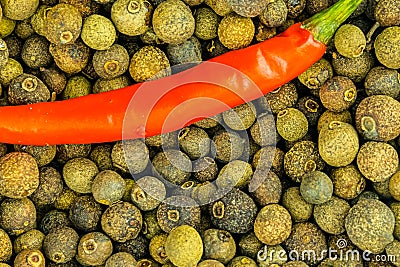 Red chili peppers large pod spicy vegetable on a background of large black peppercorns culinary base background Stock Photo