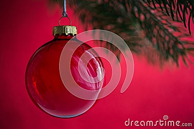 Red christmas ball on the xmas tree on red bokeh background. Merry christmas card. Stock Photo