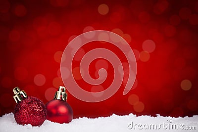 Red Christmas baubles on snow with a red background Stock Photo