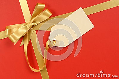 Red Christmas gift background, gold ribbon bow, blank manila gift tag or label Stock Photo