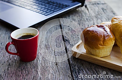 Red coffee cup and Tasty buns with latop computer on wood Stock Photo