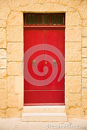 Red colored wooden door, sand stone wall in Medina city, Malta Stock Photo