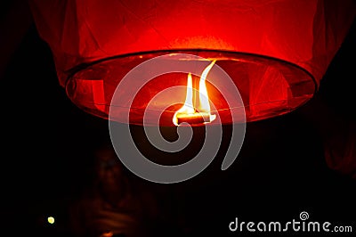 A red coloured sky lantern with the flames showing clearly lifiting off Stock Photo