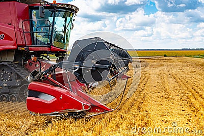 A red combine harvester with a mower in a field Stock Photo