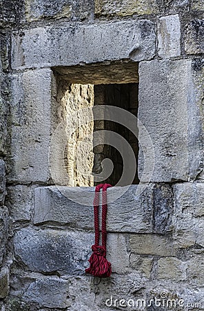 A red cord hanging out of a stone window. Generative AI. Stock Photo