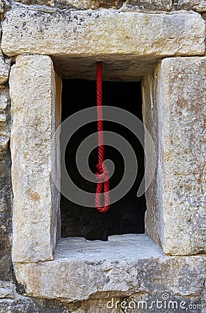 A red cord hanging out of a stone window. Generative AI. Stock Photo