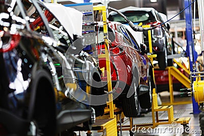 A red crossover is standing on a transport tape at a car factory. Car manufacturing. Stock Photo