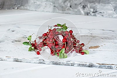 Red currant with ice and green leaves on white wooden background. Still life of food. Cubes of ice with berries. Stock Photo