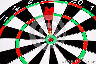 Red dart arrow hitting in the target center of dartboard Stock Photo