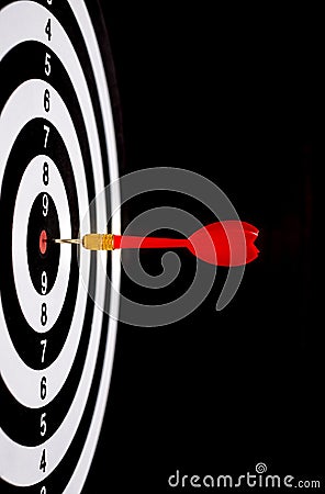 Red dart arrow hitting in the target center of dartboard Stock Photo