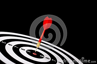 Red dart arrow hitting in the target center of dartboard Stock Photo