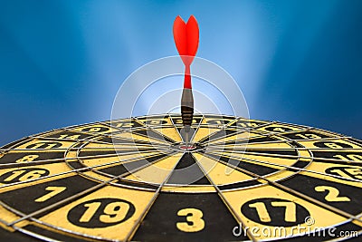 Red dart arrow hitting in the target center of dartboard Stock Photo