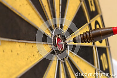 Red dart arrow hitting in the target center of dartboard Stock Photo