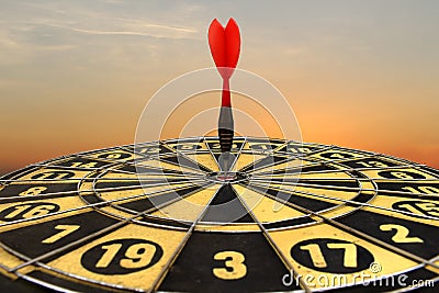 Red dart arrow hitting in the target center of dartboard Stock Photo