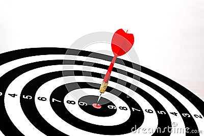 Red dart arrow hitting in the target center of dartboard Stock Photo