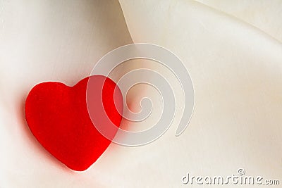 Red decorative heart on white silk background. Stock Photo