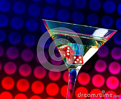 Red dice in the cocktail glass on colorful gradient bokeh Stock Photo