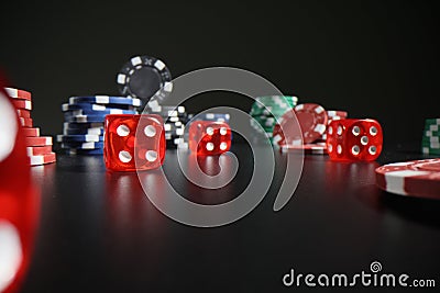 Red dice and colorful poker chips scattered on dark table Stock Photo