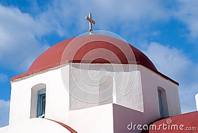 Red dome with cross detail in Mykonos, Greece. Church building architecture on sunny outdoor. Chapel on blue sky Stock Photo