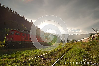 Red DR Class 130 DB Schenker locomotive and romanian CFR commuter train Editorial Stock Photo