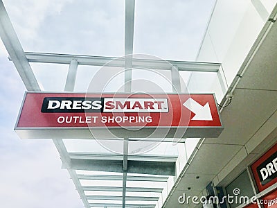 Red Dress Smart outlet shopping signs and arrow hanging outside of the building. Editorial Stock Photo