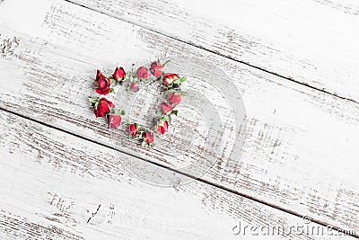 Red dry roses scattered on the light wooden background. Love Stock Photo