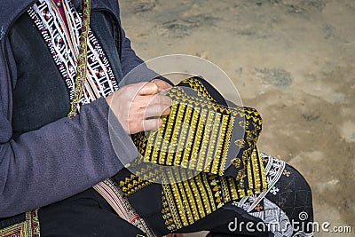 Red dzao ethnic minority woman sewing in Sa Pa, Lao Cai province, Vietnam. an elderly woman sews on street. Make beautiful Stock Photo