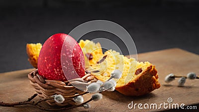 Red Easter egg in wisker stand and slice of Easter cake on a cutting board on a dark table - traditional Easter Stock Photo