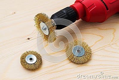 Red electric drill and three round metal wire brushes for cleaning of metal and wood and remove rust over rough wooden surface. Stock Photo