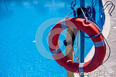Red emergency lifebuoy hanging on fence near sea or pool Stock Photo