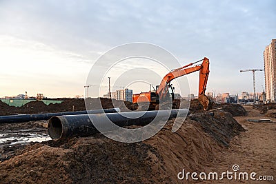 Red excavator during groundwork on construction site. Hydraulic backhoe on earthworks. Stock Photo