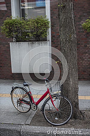 Red family bicycle with black front basket parking unattended. Stock Photo