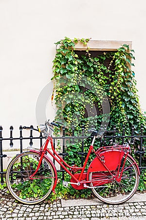 Red female bicycle leaning against a rail fence Editorial Stock Photo