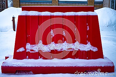 A red fence in snow on a street in winter Stock Photo