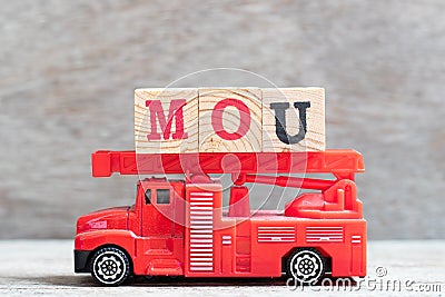 Red fire truck hold block in word MOU Abbreviation of memorandum of understanding on wood background Stock Photo