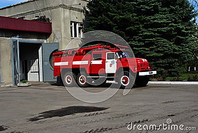 Red fire truck rides along the road from the garage to emergency call, against a background of a spring city Editorial Stock Photo